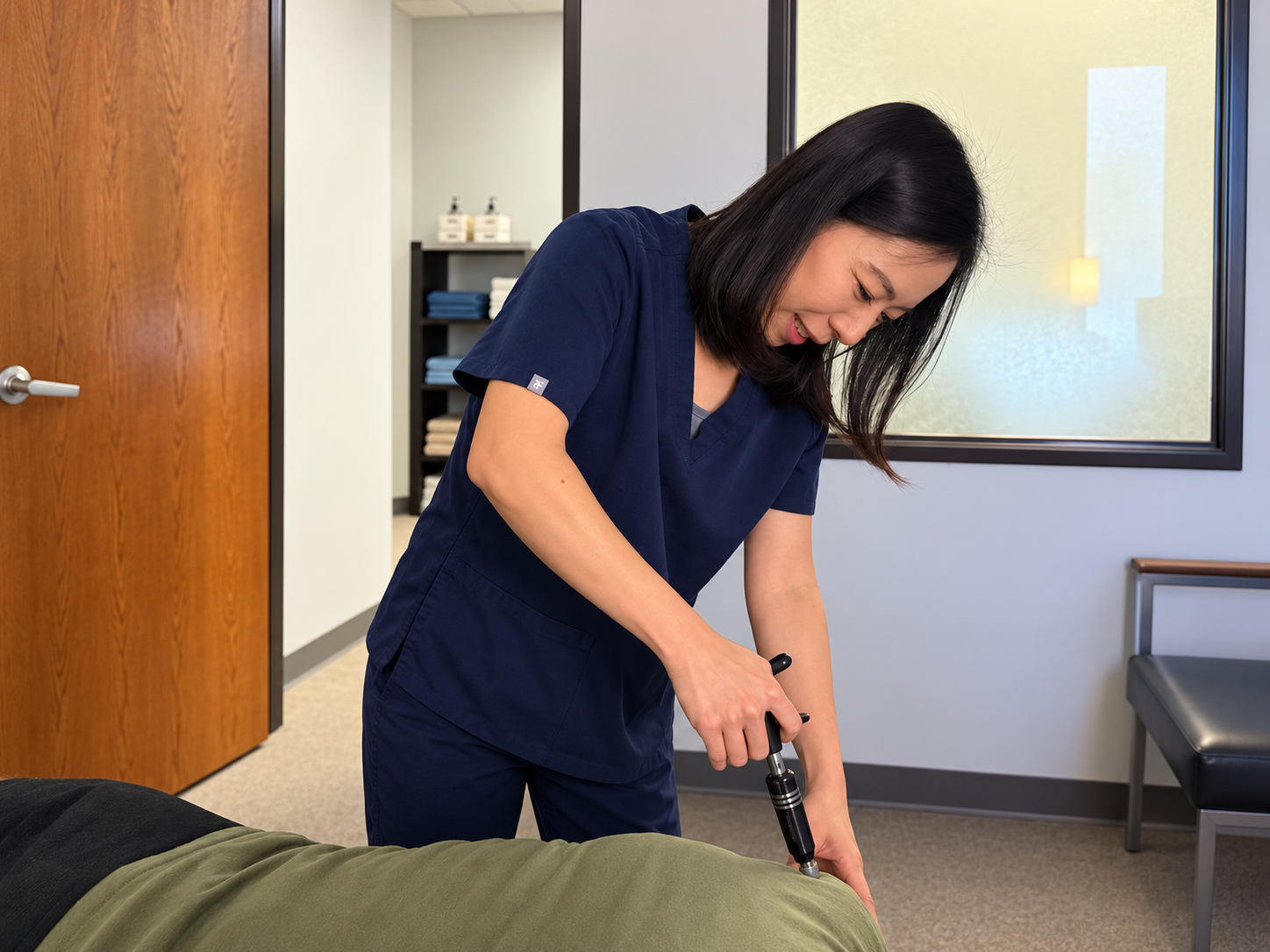 Clinician applying an Activator adjusting instrument to a patient’s back in the clinic