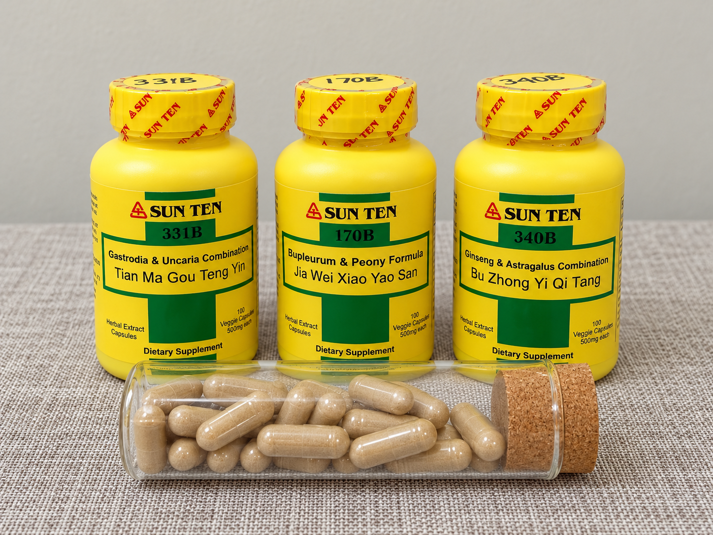 Yellow Sun Ten herbal capsule bottles and a glass vial of capsules against warm walnut slats