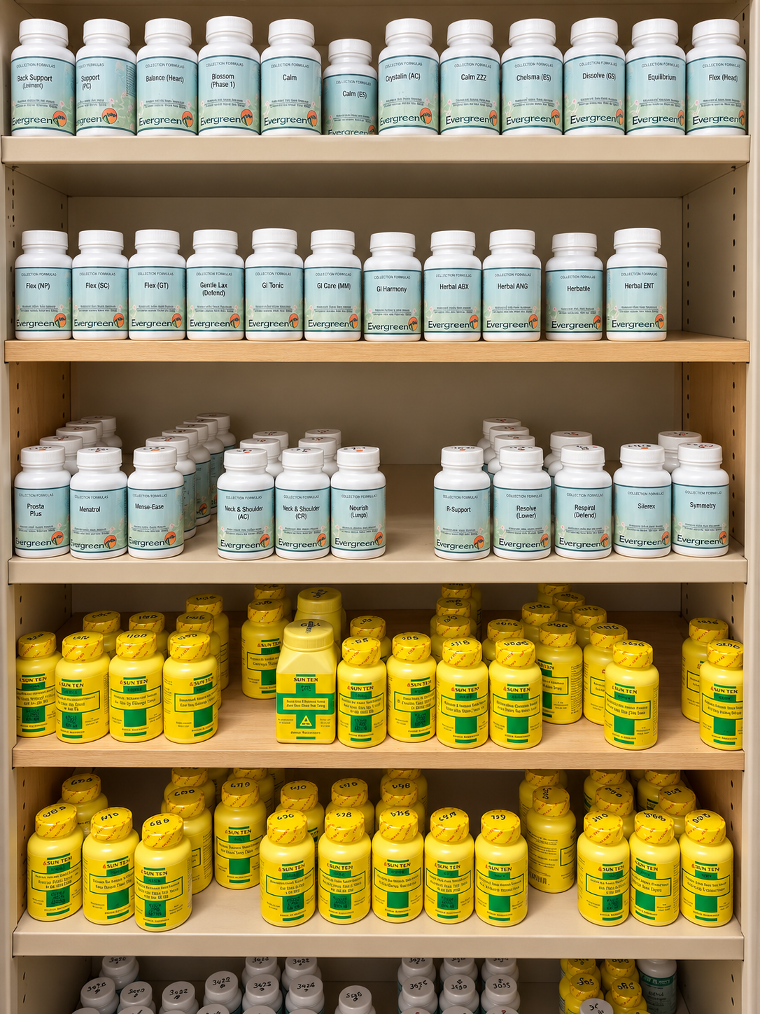 Warmly lit wooden clinic cabinet with organized Evergreen and Sun Ten herbal capsule bottles